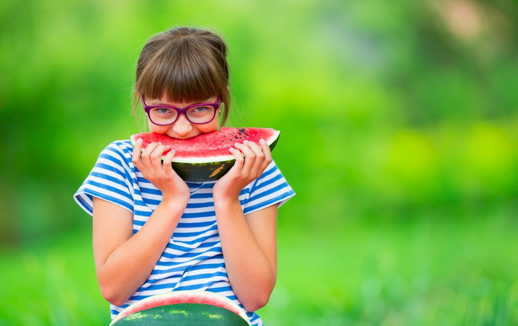 Child eating watermelon. Kids eat fruits in the garden. Pre teen girl in the garden holding a slice of water melon. happy girl kid eating watermelon. 