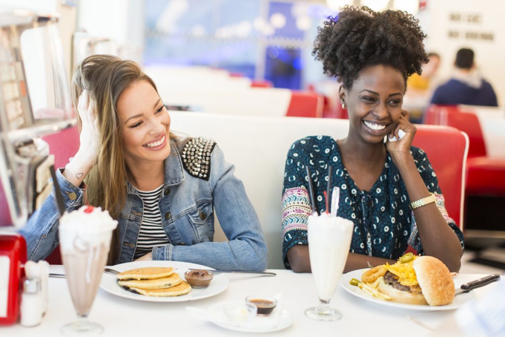close up of two women smiling at s fast food table