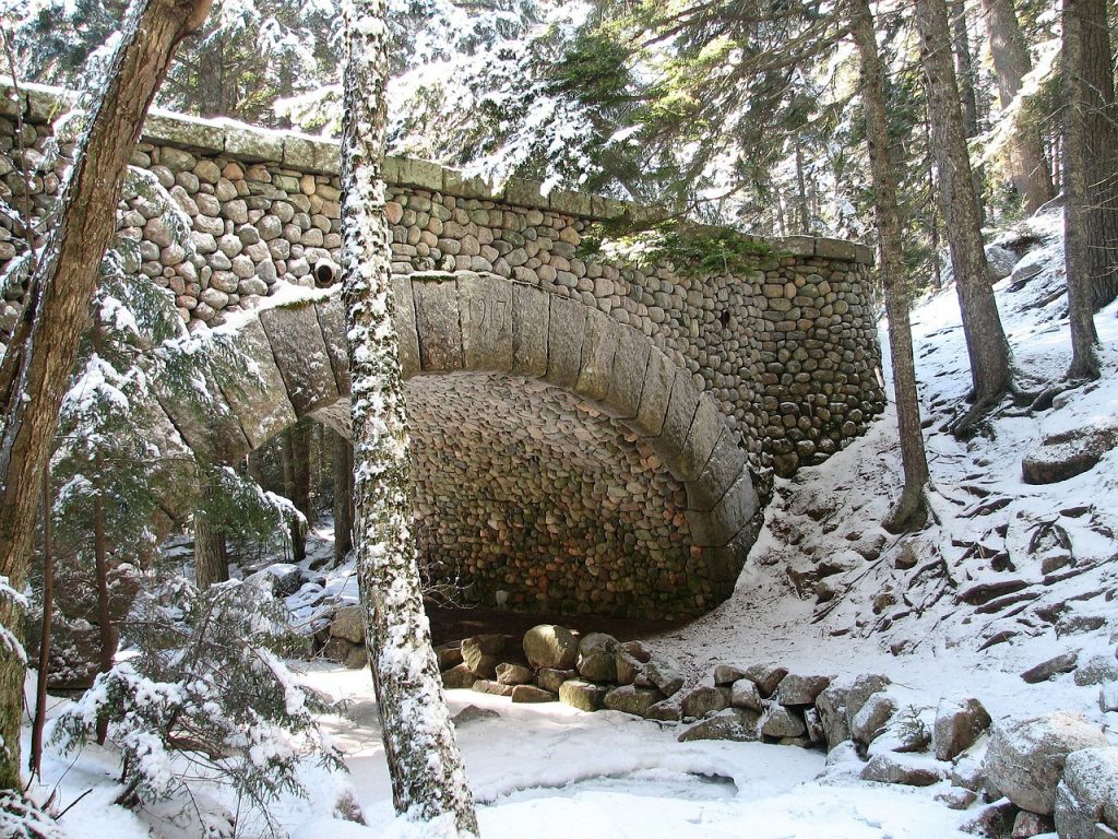 Acadia National Park bridge during winter with snow on it, frozen creek underneath
