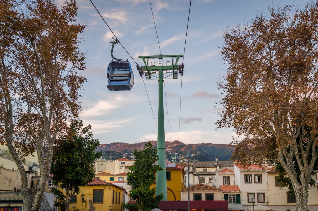 Cable car, ski lift or gondola,  going over  sunset warm light and mountain range on the background