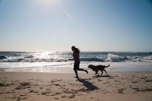 Girl and her dog playing on beach