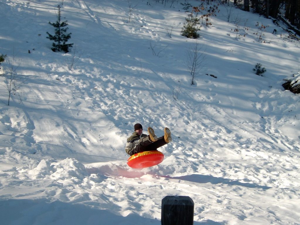man snowtubing down a hill in a red tube 