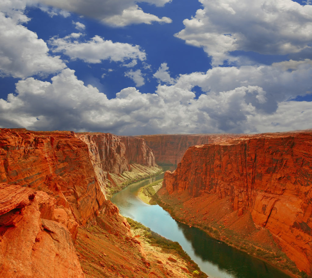 Blue skies and white clouds above the canyons and water inside Grand Canyon National Park 