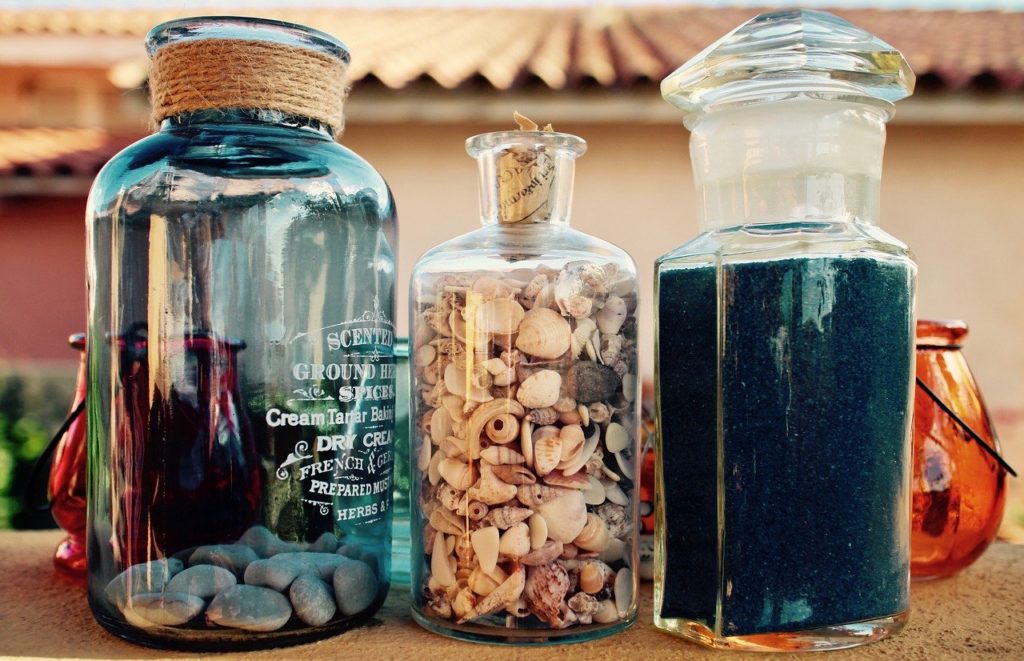 decorative jars on a table with seashells inside 